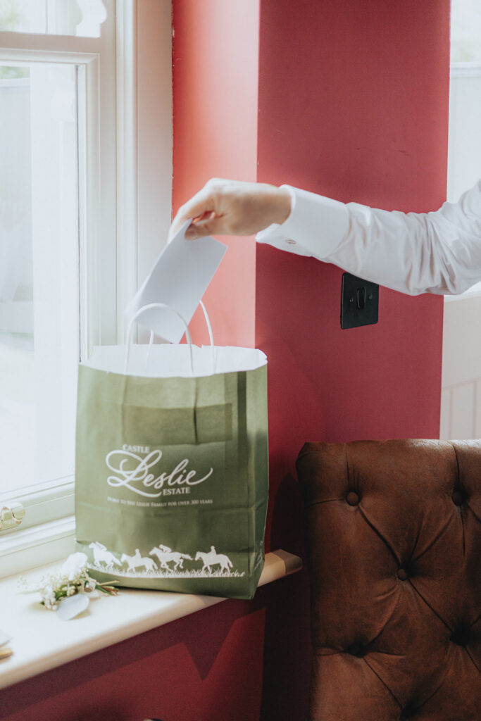 Groom opening his Gift Exchange from his bride Wedding Photos at Castle Leslie Ireland by the combs creative Weddings