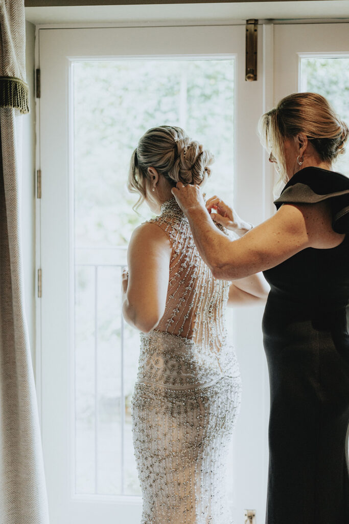 mother of the bride helping her with her wedding dress