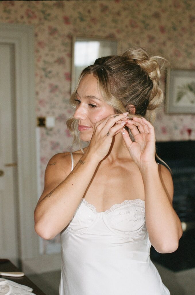 bride putting on her jewelry for her ceremony